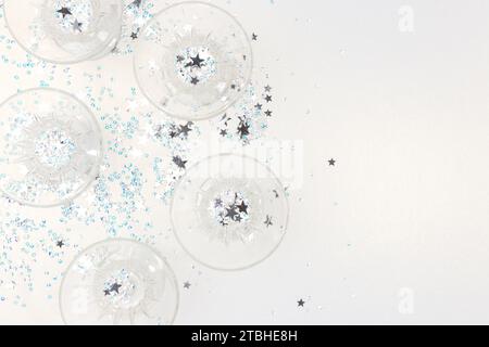 Kristallgläser und Sternenkonfetti auf silbernem glitzerndem Hintergrund. Festliches Konzept. Stockfoto