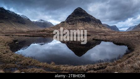 Der Berg Buachaille Etive Beag spiegelt sich in den stillen Gewässern von Lochan na Fola, Glencoe, Highland, Schottland. Frühjahr (März) 2023. Stockfoto