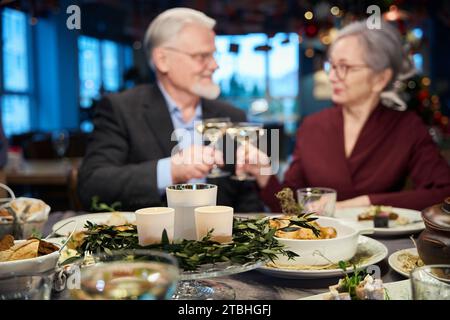 Älteres Ehepaar feiert Silvester zusammen und klirrt Gläser mit Champagner an Stockfoto