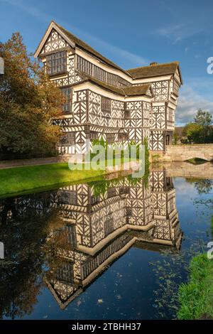 Tudor Manor Little Moreton Hall, reflektiert in seinem Graben, Congleton, Cheshire, England. Herbst (Oktober) 2023. Stockfoto