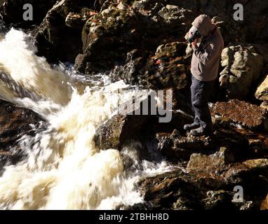 Ein Fotograf bei der Arbeit, der Bewegung und Abstraktion der Wasserfälle von Feugh bei Banchory, Aberdeenshire, Schottland, aufnimmt. Stockfoto