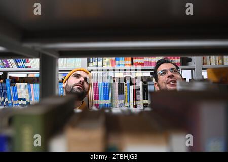 (231207) -- TIANJIN, 7. Dezember 2023 (Xinhua) -- Raydis Franco (R) und Santiago ARAG¨®n suchen nach Büchern in einem akademischen Zentrum des Kollegiums für Fremdsprachen der Nankai-Universität, nordchinesisches Tianjin, 6. Dezember 2023. Raydis Franco aus Venezuela und Santiago ARAG¨®n aus Spanien sind beide Spanischlehrer, die an der Hochschule für Fremdsprachen der Nankai-Universität im nordchinesischen Tianjin arbeiten. Von der chinesischen Kultur angezogen, begannen sie, Chinas Quergespräch auf Spanisch zu lernen und zu führen. Franco ist der Dugen, ein Hauptredner, der Schlagzeilen und Witze liefert, während ARAG¨®n die Rolle übernimmt Stockfoto