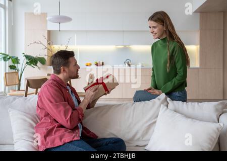 Eine strahlend lächelnde Frau, die mit Aufregung auf den Freund schaut und auf die Reaktion des Mannes wartet Stockfoto