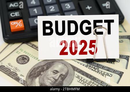 Geschäftskonzept. Auf den Dollars gibt es einen Taschenrechner und eine Visitenkarte mit der Aufschrift - BUDGET 2025 Stockfoto