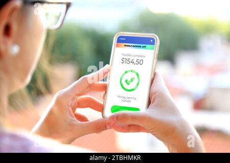 Mobiltelefon mit einer Finanzanwendung auf dem Bildschirm. Eine Frau, die Geld online überweist, indem sie Anwendungen verwendet, um Geld zu senden und zu empfangen. Geldtransferierung Stockfoto