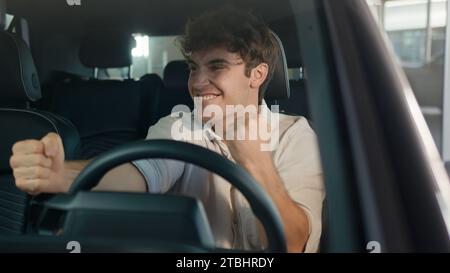 Kaukasischer Mann Fahrer männlicher Kerl Käufer Kunde Geschäftsmann sitzt im Auto feiert Erfolg Business Triumph Leistung Kauf neues Auto Stockfoto
