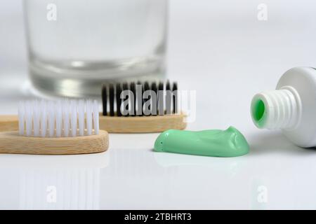 Glaswasser, zwei hölzerne Zahnbürsten und grüne Nadelzahnpasta im Badezimmer Stockfoto