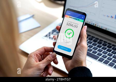 Mobiltelefon mit einer Finanzanwendung auf dem Bildschirm. Geschäftsfrau, die Geld online mit Anwendungen überweist, um Geld zu senden und zu empfangen. Geld Stockfoto