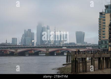 Skyline der Stadt London mit Wolkenkratzern, die an einem Wintertag in Nebel gehüllt sind. Leute, die am Oxo Tower auf der Oxo Tower Wharf vorbeilaufen. South Bank, London, Großbritannien Stockfoto