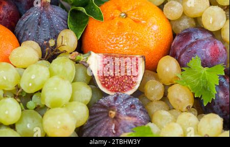 Helle Orange Mandarine, Feigen und Traubenfrucht Mischung mit grünen Blättern, gesunde Lebensmittel Hintergrund Stockfoto