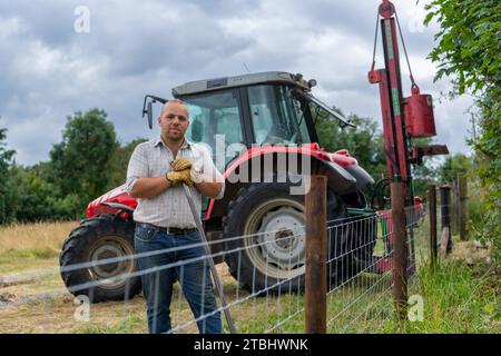 Zaununternehmer mit Werkzeugen seines Gewerbes, die einen Viehzaun aus Drahtgeflecht errichten. Co. Durham, Großbritannien. Stockfoto