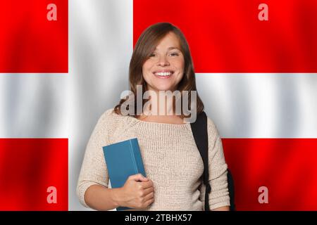 Freundliche Studentin vor dänischem Flaggenhintergrund. Reisen, Bildung und Sprachenlernen in Dänemark Konzept Stockfoto
