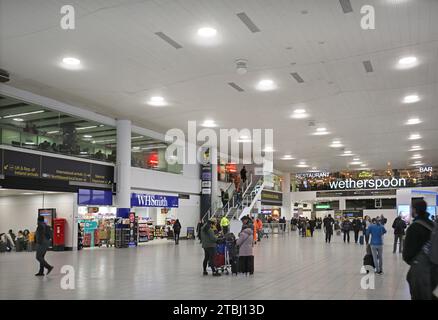 Flughafen Gatwick, Südterminal, Check-in-Bereich. Zeigt Passagiere, Abfahrtstafeln, Geschäfte und Restaurants. Stockfoto