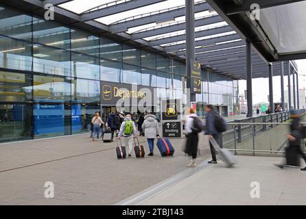 Flughafen Gatwick, Großbritannien, Nordterminal, Eingang für Abflüge, Außenansicht. Passagiere betreten mit Gepäck (verschwimmen durch Bewegung). Stockfoto