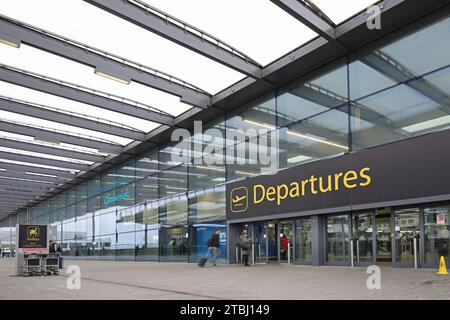 Flughafen Gatwick, Großbritannien, Nordterminal, Eingang für Abflüge, Außenansicht. Passagiere betreten mit Gepäck (verschwimmen durch Bewegung). Stockfoto