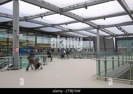 Flughafen Gatwick, Großbritannien, Nordterminal, Eingang für Abflüge, Außenansicht. Passagiere betreten mit Gepäck (verschwimmen durch Bewegung). Stockfoto