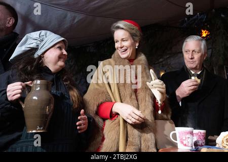 Dresden, Deutschland. Dezember 2023. Königin Mathilde (M) und König Philippe von den Belgiern trinken Glühwein während eines Besuchs auf dem Weihnachtsmarkt in Neumarkt. Das belgische Königspaar ist zu einem dreitägigen Staatsbesuch nach Deutschland gekommen. Quelle: Sebastian Kahnert/dpa/Alamy Live News Stockfoto