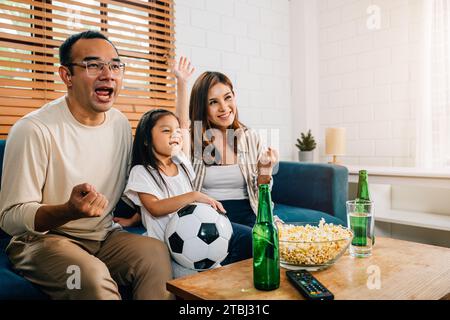 Eine glückliche Familie genießt den Nervenkitzel eines Fußballspiels zu Hause Stockfoto