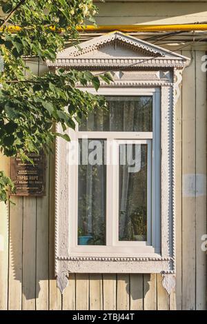 Jelabuga, Russland - 18. Juni 2023: Typisches Fenster mit Holzschnitzereien an der Fassade eines Wohngebäudes aus dem späten 19. Jahrhundert. Historische Zitate Stockfoto