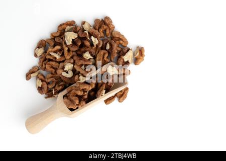Hölzerne Schaufel mit schalenförmigen Walnüssen isoliert auf weißem Hintergrund, Haufen gerösteter Nüsse in Nahaufnahme, Snack-Food-Konzept, vegane Mahlzeit Stockfoto