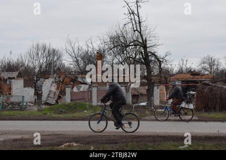 Orichhiv, Ukraine. Dezember 2023. Die Anwohner fahren mit ihren Fahrrädern die Straße entlang der privaten Häuser, die durch russische Bombardierungen in Orichschiv zerstört wurden. Der ukrainische Präsident Wolodymyr Zelenskyj sagte, er habe eine Erweiterung der Verteidigungsanlagen über das Schlachtfeld angeordnet. Nach dem Scheitern der ukrainischen Gegenoffensive von 2023 könnte Zelenskyj die Ankündigung signalisieren, dass Kiew beabsichtigt, 2024 eine defensive Haltung einzunehmen. Wenn man sich hineingräbt, könnte die Ukraine dabei helfen, künftige russische Offensiven abzuwehren, während Kiew mehr Truppen für die Ausbildung im Westen ersparen kann. (Bild: © Andriy Andriyenko Stockfoto