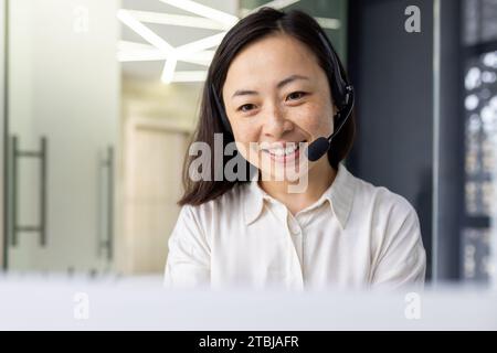 Asiatische weibliche Online-Kundenbetreuung Kundendienstmitarbeiter am Arbeitsplatz im Büro, Frau, die das Headset-Telefon für Videoanrufe verwendet, Geschäftsfrau, die auf der Laptop-Tastatur schreibt. Stockfoto