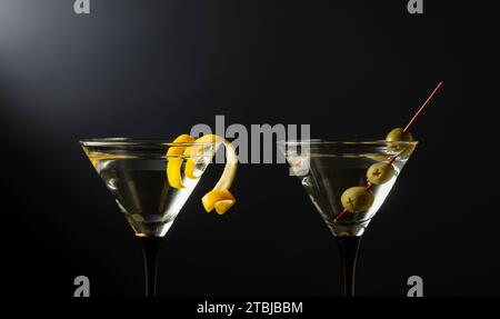 Klassische trockene Martini-Cocktails mit grünen Oliven und Zitronenschalen auf schwarzem Hintergrund. Freier Platz für Ihren Text. Stockfoto