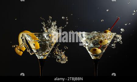 Klassische trockene Martini-Cocktails mit grünen Oliven und Zitronenschalen auf schwarzem Hintergrund. Martini mit Spritzern. Freier Platz für Ihren Text. Stockfoto