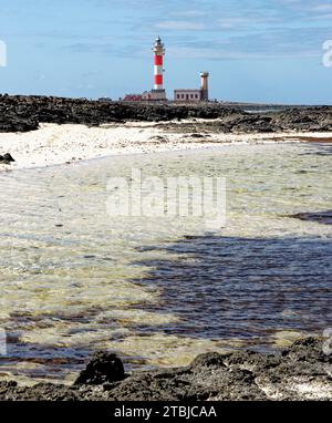 Natürliche Gezeitenbecken am Strand Playa de los Charcos und Leuchtturm von Toston - natürliche Pools am Strand von Los Laguitos oder Los Charcos auf Fuerteventura, Stockfoto