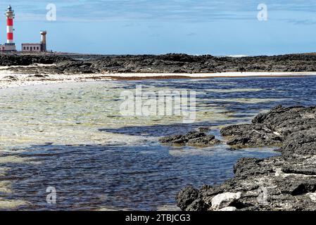 Natürliche Gezeitenbecken am Strand Playa de los Charcos und Leuchtturm von Toston - natürliche Pools am Strand von Los Laguitos oder Los Charcos auf Fuerteventura, Stockfoto