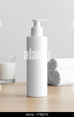 Weiße Kosmetik Shampoo Spender Flasche Modell mit einer Kerze und Handtüchern auf dem Holztisch. Stockfoto