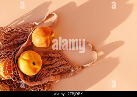 Reife Pfirsiche in Öko-Tasche auf rosa Hintergrund in natürlichem Licht, Draufsicht Stockfoto