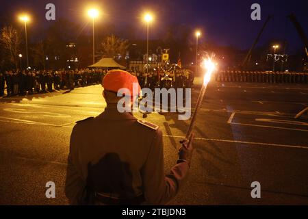 Gera, Deutschland. Dezember 2023. Ein Bundeswehrsoldat steht mit einer Fackel in der Hand bei der öffentlichen Vereidigung für rund 100 Rekruten der 5. Kompanie des Panzeringenieurbataillons 701 auf dem Parkplatz Hofwiesen. Quelle: Bodo Schackow/dpa/Alamy Live News Stockfoto