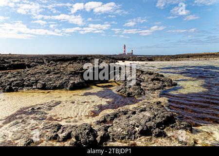 Natürliche Gezeitenbecken am Strand Playa de los Charcos und Leuchtturm von Toston - natürliche Pools am Strand von Los Laguitos oder Los Charcos auf Fuerteventura, Stockfoto