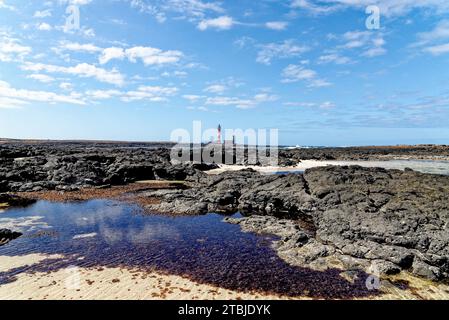 Natürliche Gezeitenbecken am Strand Playa de los Charcos und Leuchtturm von Toston - natürliche Pools am Strand von Los Laguitos oder Los Charcos auf Fuerteventura, Stockfoto