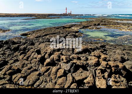 Natürliche Gezeitenbecken am Strand Playa de los Charcos und Leuchtturm von Toston - natürliche Pools am Strand von Los Laguitos oder Los Charcos auf Fuerteventura, Stockfoto