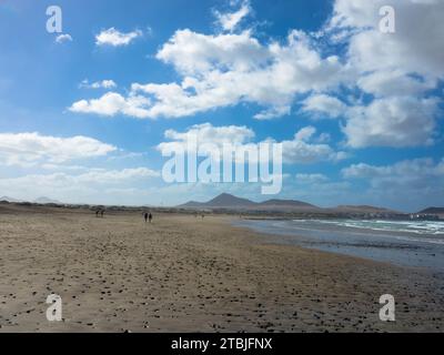 Panoramablick auf den Strand von Famara. Der beliebte Surfstrand auf Lanzarote. Im Hintergrund die Berge des Risco de Famara. Kanarische Inseln, Spanien, Europa Stockfoto