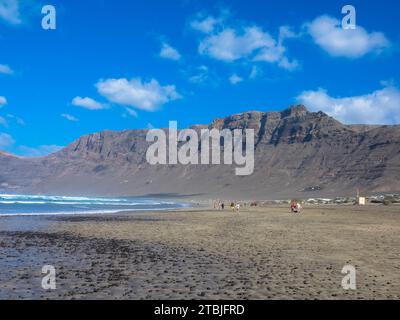 Panoramablick auf den Strand von Famara. Der beliebte Surfstrand auf Lanzarote. Im Hintergrund die Berge des Risco de Famara. Kanarische Inseln, Spanien, Europa Stockfoto