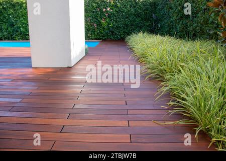 Hartholzterrasse mit immergrünem Zaun und Pool, exotische Holzterrasse Idee Stockfoto