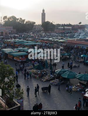 Man schiebt einen Wagen zwischen einem geschäftigen Marktplatz von Jemaa el-Fnaa an einem Winterabend in Marrakesch aka Marrakesch, Marokko, am 6. Dezember 2023 Stockfoto