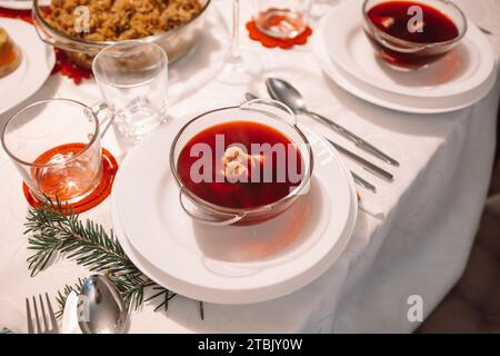 Weihnachtssuppe Rote Bete, Borschtsch mit kleinen Knödeln mit Pilzfüllung in einer Keramikschale auf einem Tisch. Traditionelles Weihnachtsgericht in Polen. Stockfoto