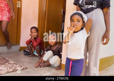 Dorf, afrikanische Familie sitzt vor dem Haus, Mutter mit Kindern Stockfoto