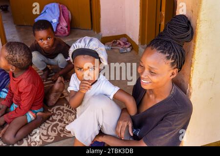 Dorf, afrikanische Familie sitzt vor dem Haus, Mutter mit Kindern Stockfoto