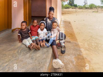 Dorf, afrikanische Familie saß vor dem Haus, Mutter mit vier Kindern Stockfoto