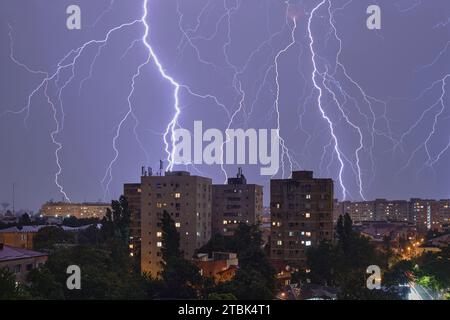 Mehrere Blitze und Gewitter über Stadtgebäuden, nachts. Wetterphänomene. Stockfoto
