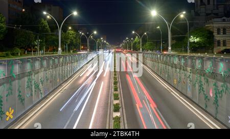 Unterqueren Sie den Autoverkehr bei Nacht, während Autos durch einen Innenstadttunnel namens Pasajul Unirii fahren, ein Wahrzeichen in Bukarest, Rumänien. Stockfoto