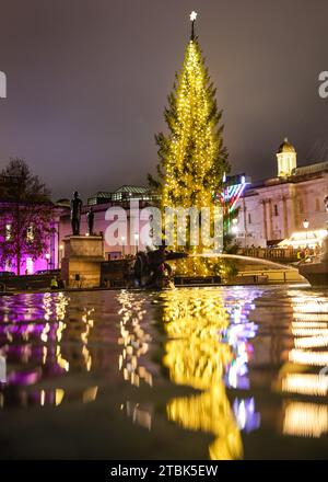 London, Großbritannien. Dezember 2023. Der beleuchtete Baum mit den Springbrunnen und Menora im Hintergrund. Die jährliche Zeremonie zum Einschalten des Weihnachtsbaums am Trafalgar Square sorgt für eine festliche Atmosphäre im Zentrum Londons, darunter Weihnachtslieder und Chorgesang. Jeden Dezember schickte ein Baum von Norwegen nach London als Geschenk, um Großbritannien für seine Unterstützung während des Zweiten Weltkriegs zu danken. Quelle: Imageplotter/Alamy Live News Stockfoto