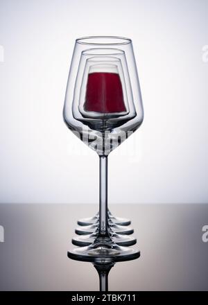 Gläser Wein, die vor einander ausgerichtet sind, auf weißem Hintergrund Stockfoto