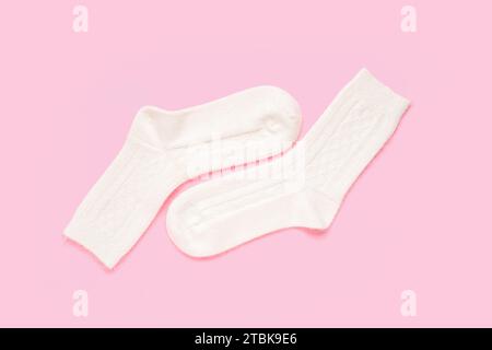 Weiße gestrickte Socken auf rosa Hintergrund Stockfoto