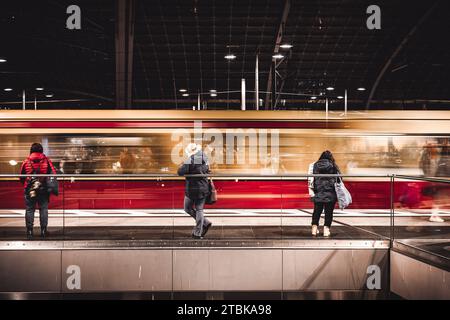 Eine Gruppe von Menschen steht Seite an Seite an Seite an einem belebten Bahnhof und wartet gespannt auf die Ankunft der nächsten Zugfahrt Stockfoto